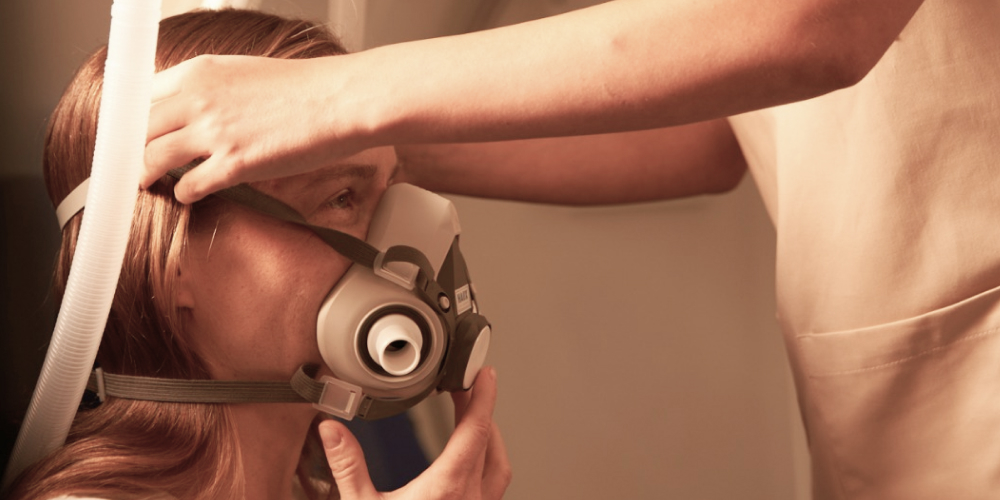 Personel medyczny pomaga nałożyć pacjentce maskę tlenową w komorze hiperbarycznej