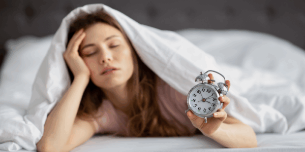 Kobieta trzymająca budzik cierpiąca na zaburzenia snu