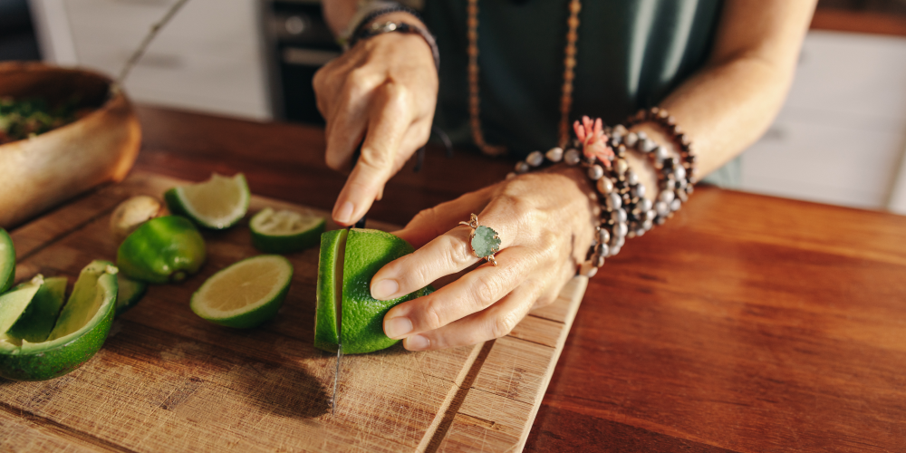 Kobieta krojąca limonkę na drewnianej desce – przygotowanie świeżych składników do zdrowego posiłku wspierającego organizm w okresie menopauzy.