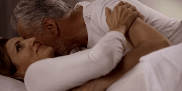 Dojrzała para przytulająca się w łóżku – bliskość, czułość i radość z życia intymnego w dojrzałym wieku jako efekt zdrowego stylu życia i odpowiedniej diety wspierającej libido.