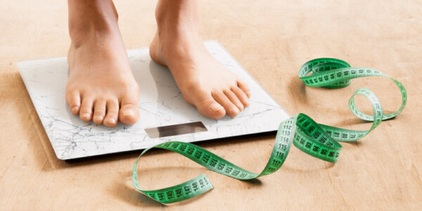 Stopy na wadze i centymetr, symbol zmieniającego się metabolizmu