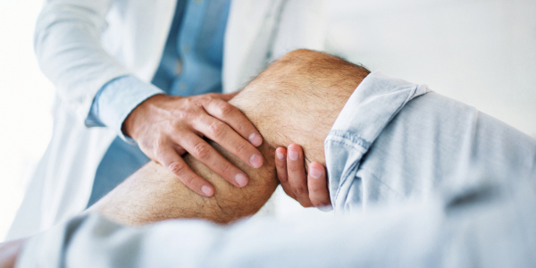 Lekarz badający staw pacjenta przed alloplastyką stawu kolanowego.