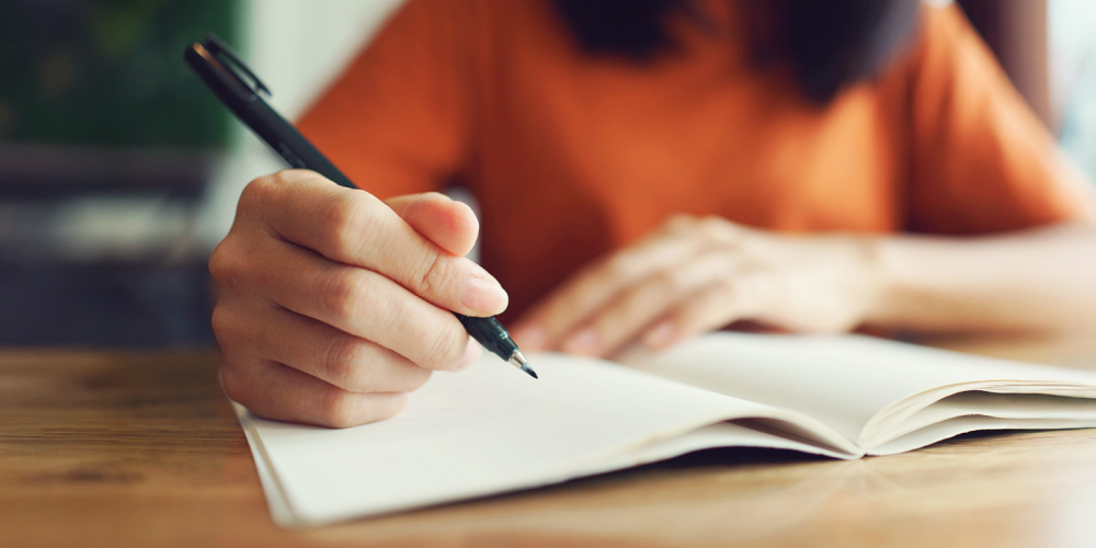 Osoba pisząca w notesie – Pisanie nowych celów – postanowienia na 2026 rok w duchu longevity.