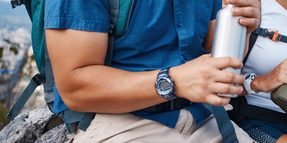 Mężczyzna próbujący odkręcić butelkę z wodą pomimo objawów łokcia tenisisty.