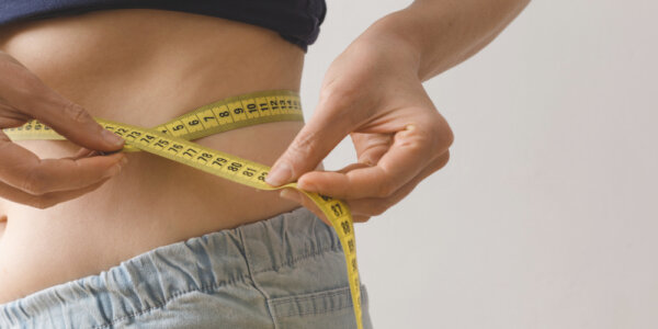 Woman measuring her body circumferences to monitor body weight